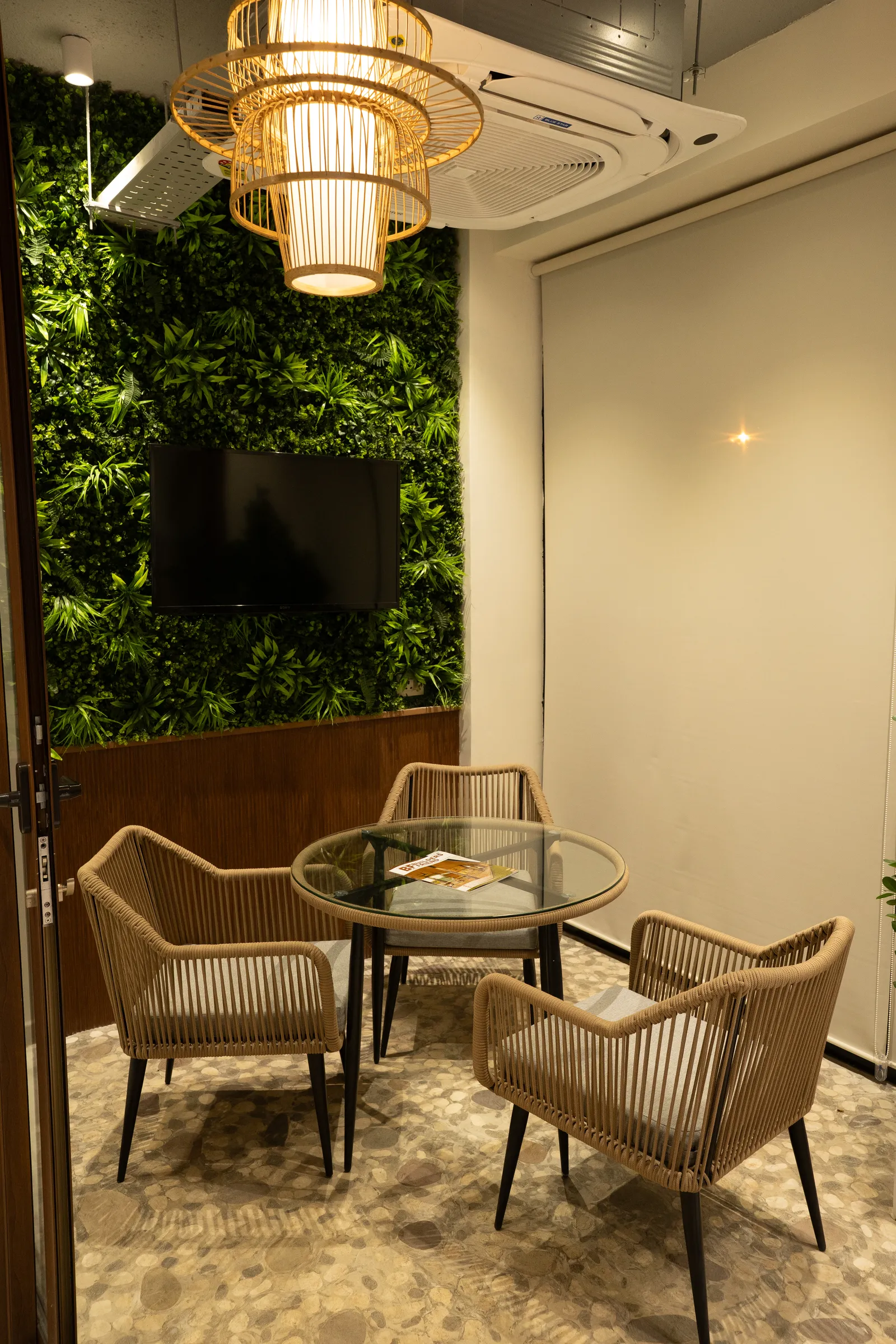 Lounge corner with green wall and rattan chairs — Aluk Experience Center